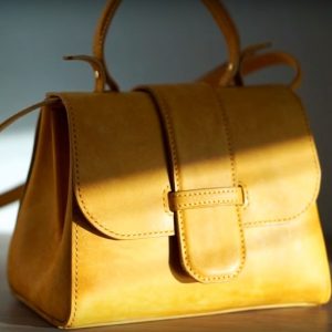 Выкройка небольшой женской кожаной сумочки на белом фоне.