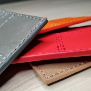 Выкройка кожаной визитницы для банковских карт с несколькими карманами на белом фоне.