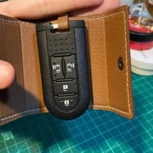 Выкройка кожаного чехла для ключей от машины на белом фоне.